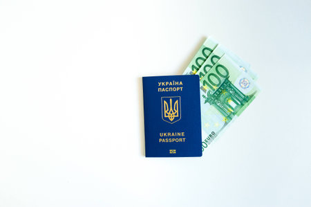 Ukraine passport with Euro Bills inside. On a white background with filler coins.