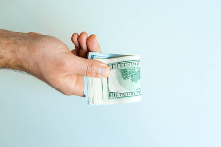 men's hand with big bundle of american dollars on white backgroundの写真素材
