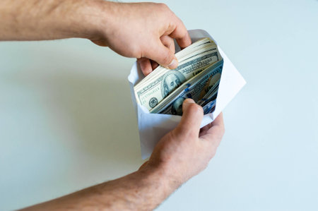 Closeup of man's hands with envelope full of dollar banknotes on white background. Concept of corruption and briberyの写真素材