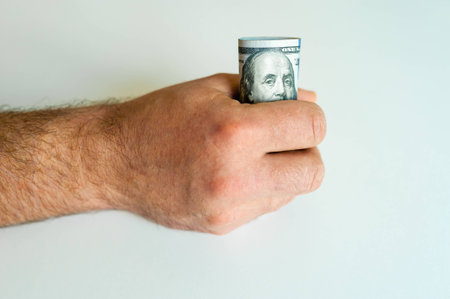 men's hand with big bundle of american dollars on white backgroundの写真素材