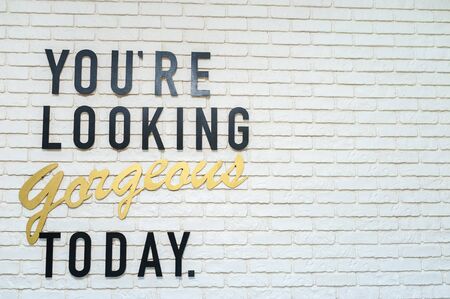 Inscription blank on a white brick wall. You're looking gorgeous todayの写真素材