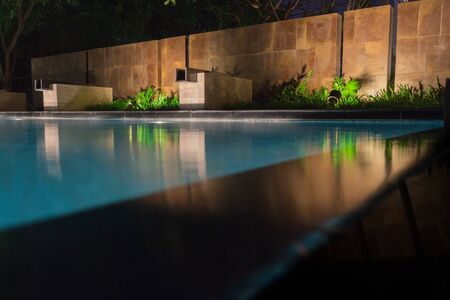 Peaceful pool reflections looking toward mood lighting and lush greenery giving soft shadows onto the stone.  This warm water at dusk is a perfect place for swimming in luxury at millionaires mansion.の写真素材