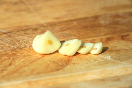 Finely sliced garlic on a wooden board with slanted shadows.の写真素材
