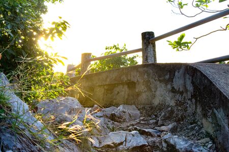 Haunted footpath along the ocean at sunset with an eerie glow and dangerous rocks along the walkway with derelict old metal railing.の写真素材