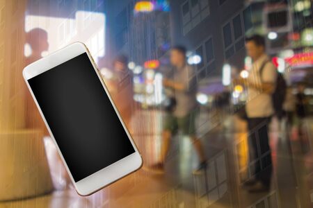 Window shopping city concept with empty phone template.  Asian men shopping and using the internet on their phones outside at night in the city center.  Copy space.の写真素材
