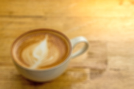 Blurred cup of creamy cappucino on wooden desk with lots of room for copyspace.  This yummy and delicious creamy drink is part of your morning routine and helps you wake up.  Organic beans.の写真素材