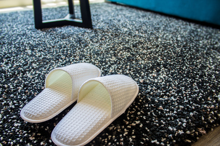 Cozy warm slippers on plush carpet for comfort and warmth in modern living room.の写真素材