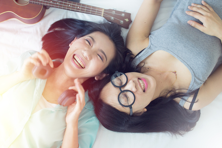 Two asian girls for lesbian love concept with happy emotion laying on bed in a happy in relationship together.の写真素材
