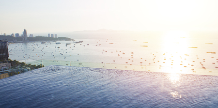 Infinity pool with city and ocean view at dusk with sunset and soft tropical breeze.  Panorama wide angle with copy space for words.の写真素材