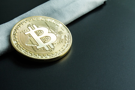 Learn how to invest on crypto exchange.  Physical golden bitcoin on white cloth.