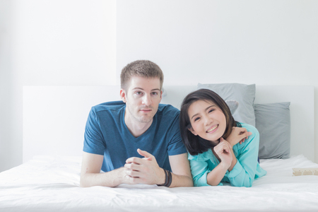 Couple with good communication skills.  White background laying on bed and happy.の写真素材