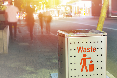 Trash bin on street sidewalk in the night with traffic and urban city lifestyle surrounding it.  World garbage and trash awareness.の写真素材