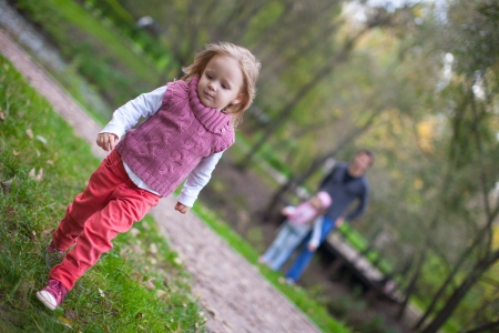 Portrait of little girl close-up and her father and sister in the backgroundの写真素材