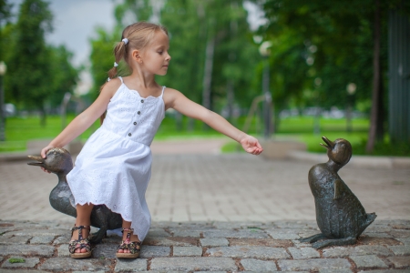 Little girl feeding the ducks figure in the parkの写真素材