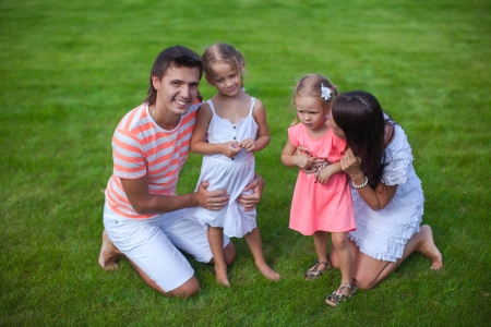 Portrait young family of four sit on the grass and have funの写真素材