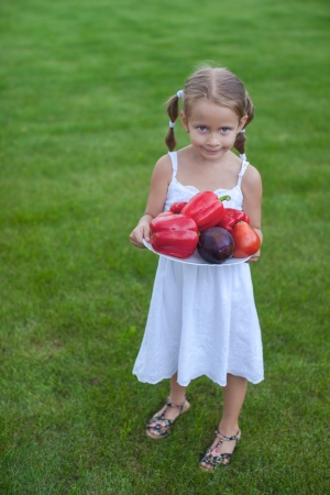 Lovely girl in a garden with a plate of vegetablesの写真素材