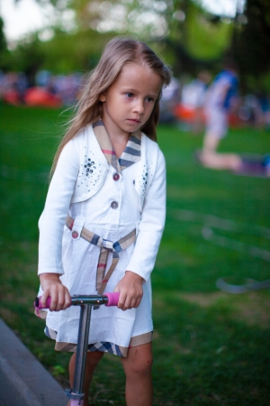 Beautiful toddler girl on the scooter in a parkの写真素材