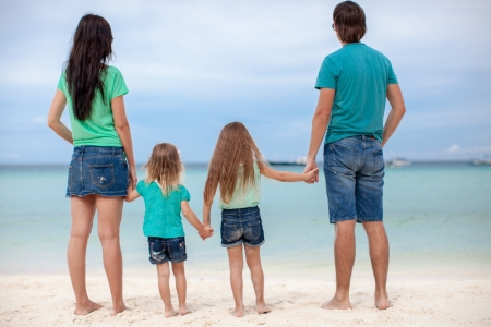 Back view of beautiful family with two kids at exotic beachの写真素材
