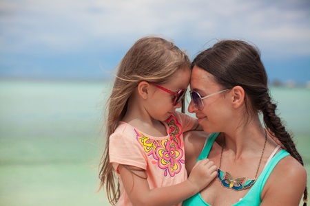 Portrait of a little girl hugging with her mother on the beachの写真素材