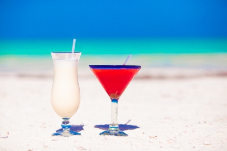 Two cocktails  pina colada and strawberry margarita on white sand beachの写真素材