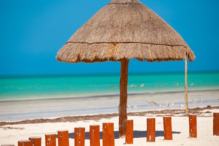 Big straw umbrella at the white sand beach