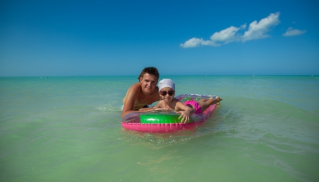 Young father with young daughter on an air mattress in the seaの写真素材
