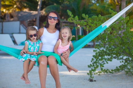 Fashion mother and  her daughters relaxing in hammock in exotic resortの写真素材
