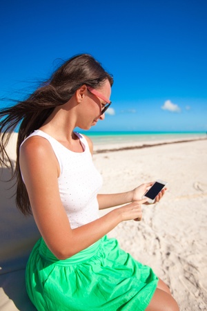 Young girl enjoys her phone on an exotic beachの写真素材