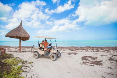 General view golf car with family inside on an exotic beachの写真素材
