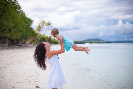 Young mother and her cute daughter have fun on exotic beachの写真素材