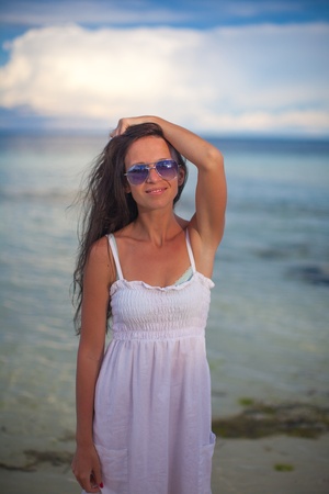 beautiful young girl standing in the water at beach and looking in cameraの写真素材