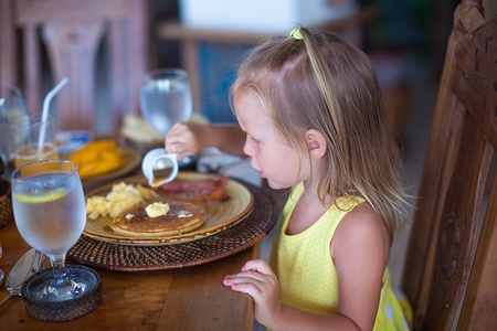Adorable little girl having breakfast at resort restaurantの写真素材