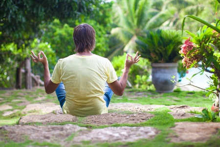 Young man sitting in the lotus position in the garden in beautiful resortの写真素材