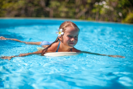 Little cute happy girl swims in the swimming poolの写真素材