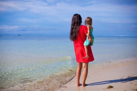 Back view of mother and her little daughter looking at the seaの写真素材