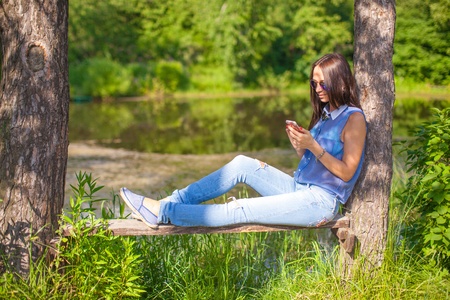 Young woman walking outdoors and looking at the phoneの写真素材