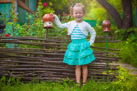 Adorable little girl standing near vintage wooden rural fence and smilingの写真素材