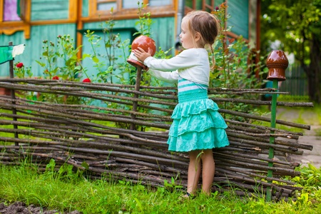Adorable little girl standing near vintage wooden rural fenceの写真素材