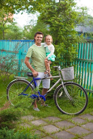 Young father and cute little daughter near the bicycle on rural roadの写真素材