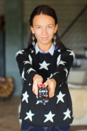 Close up portrait of woman with remote control inside her houseの写真素材