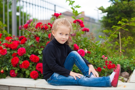 Portrait of cute little girl near the flowers in the yard of her houseの写真素材