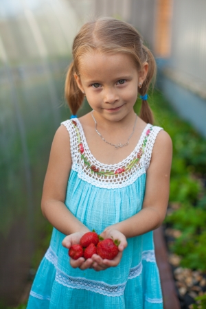 Portrait of cute little girl in the garden with berries in her handsの写真素材