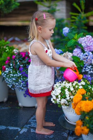 Little cute girl watering flowers with a watering canの写真素材