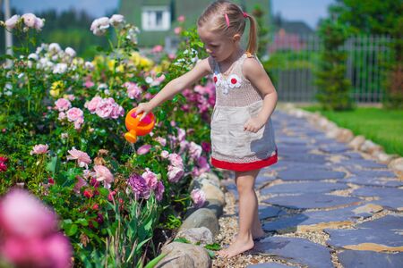Adorable cute girl watering flowers with a watering canの写真素材