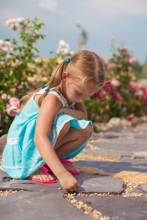 Cute small girl drawing on the sidewalk with chalk in the yardの写真素材