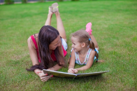 young mother and her cute daughter reading a book and enjoying the holidayの写真素材