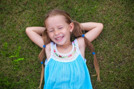 Little girl lying on the grass and laughs