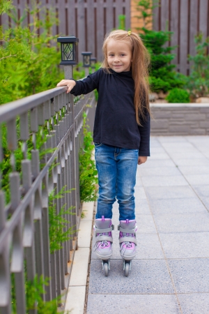 Little cute girl on roller skates in front of her homeの写真素材