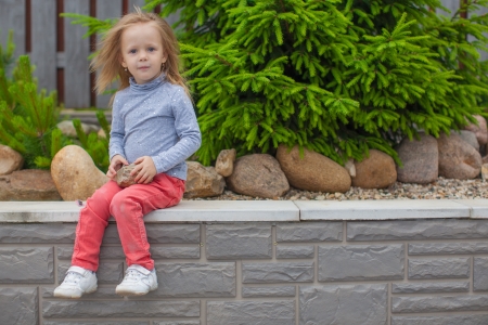 Adorable little girl sitting in the garden in her yardの写真素材