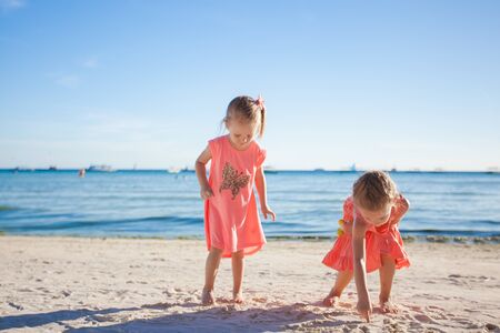 Two little sisters playing together on the white beachの写真素材